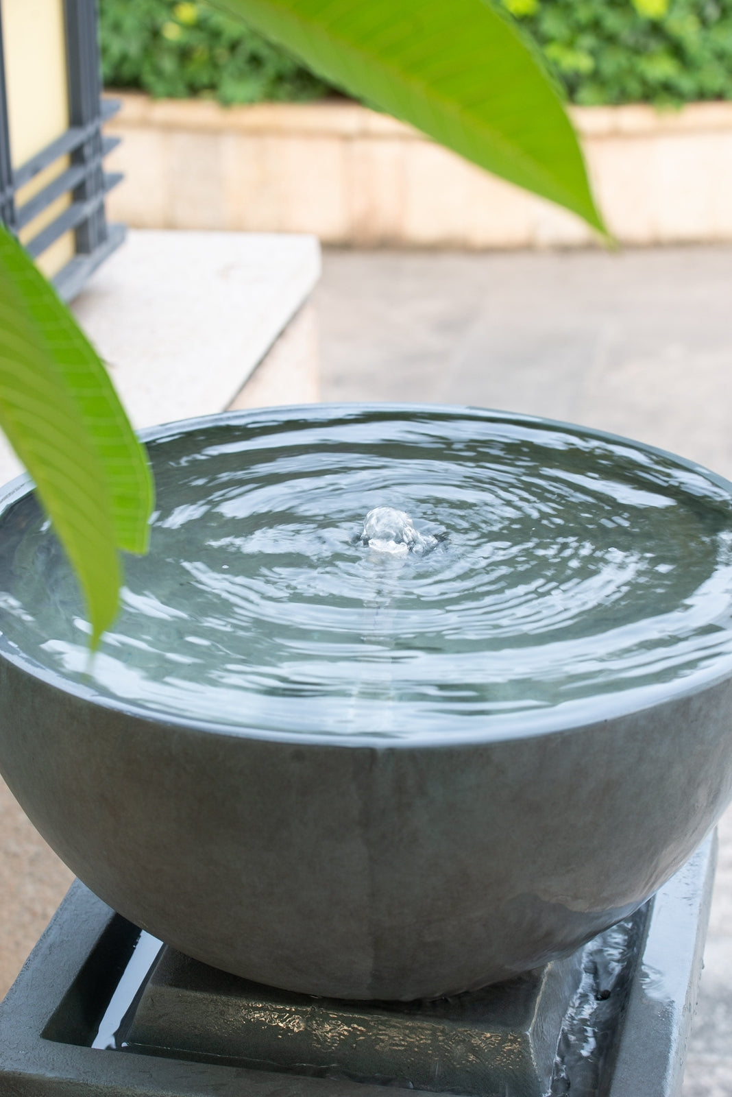 Close view of the bubbling bowl of the Resin Zen Bowl Pedestal Outdoor Fountain 44 Inch on a patio.