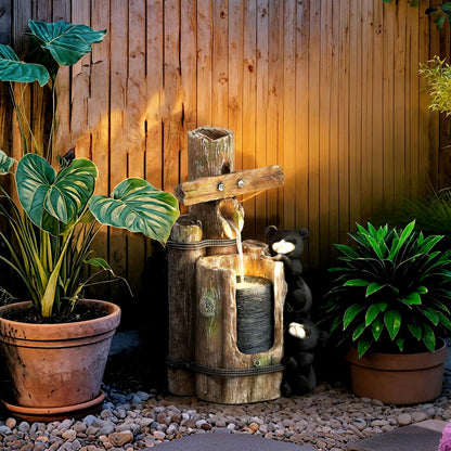 Resin Bear Fountain Two Cubs on Timber Post with water flowing between potted plants by a wooden fence.
