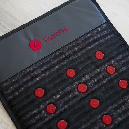 Close-up of the TheraPro™ PEMF pad’s red logo, textured surface, and circular red elements.
