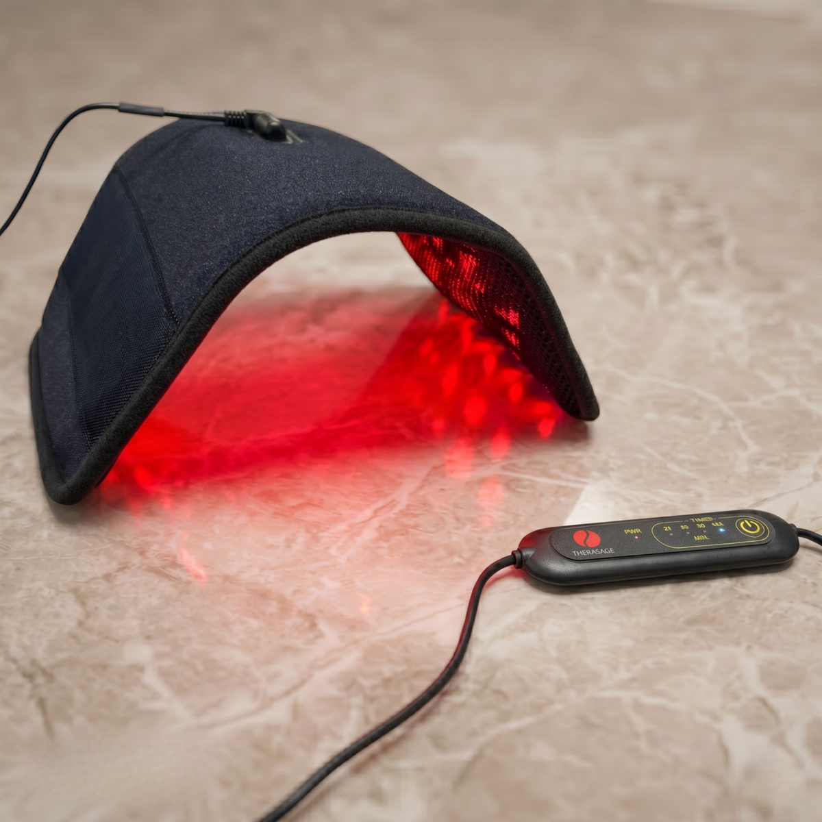 Therasage Tri-Lite™ Red Light Therapy Panel arches over a light stone surface, glowing red beside its wired controller.