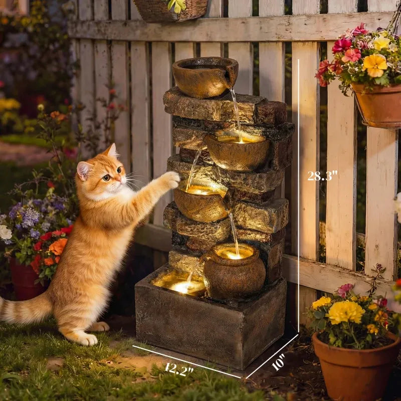 Resin Stacked Stone Bowl Cascade Fountain 28 Inch beside a ginger cat reaching toward a bowl in a flower-filled yard.