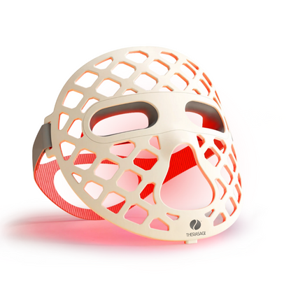 TheraGlow Mask2Go+™ LED Light Therapy Face Mask shown at an angle with red light glowing through its open lattice.