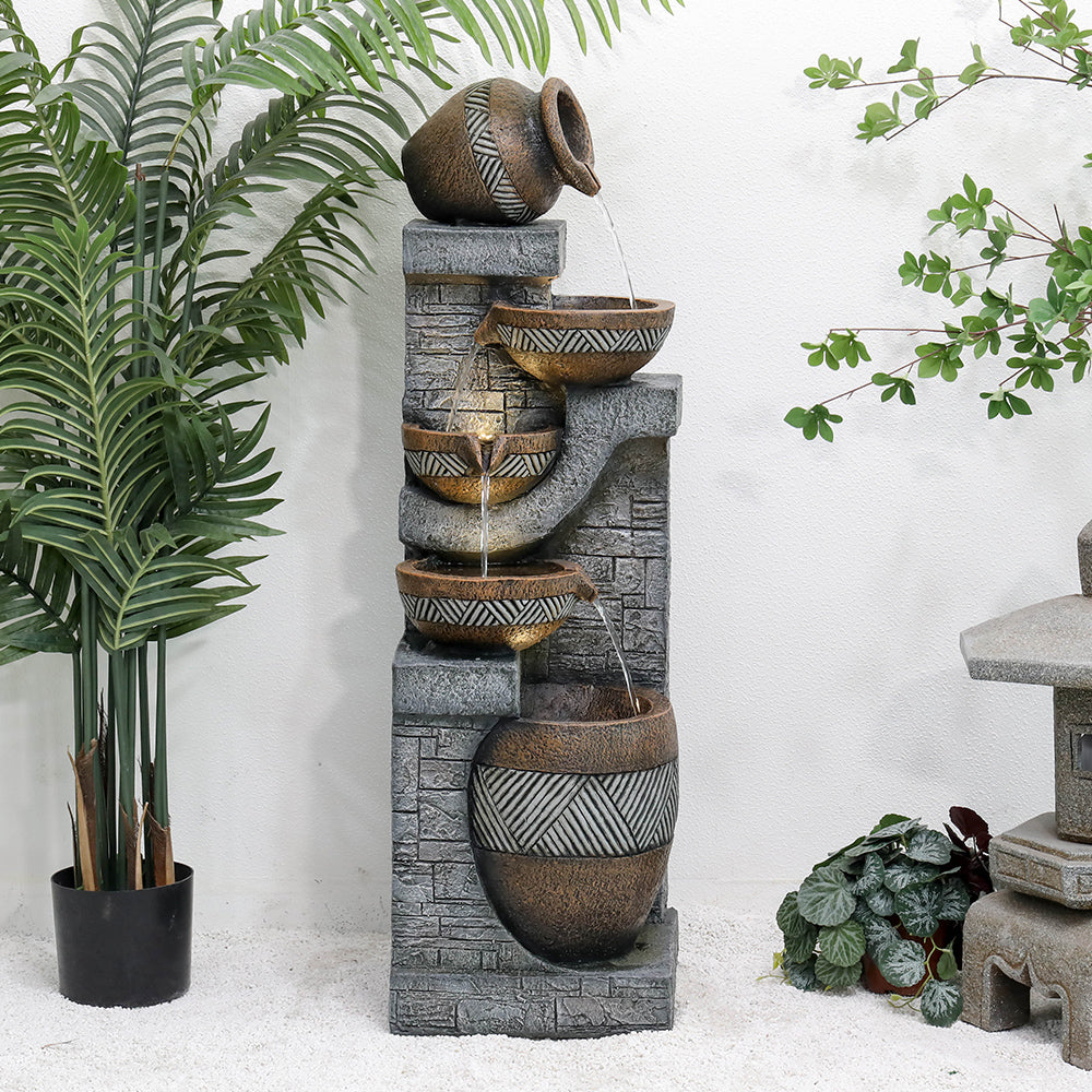 Resin Carved Clay Urn Outdoor Water Fountain 42 Inch shown with water flowing into patterned bowls beside potted plants.