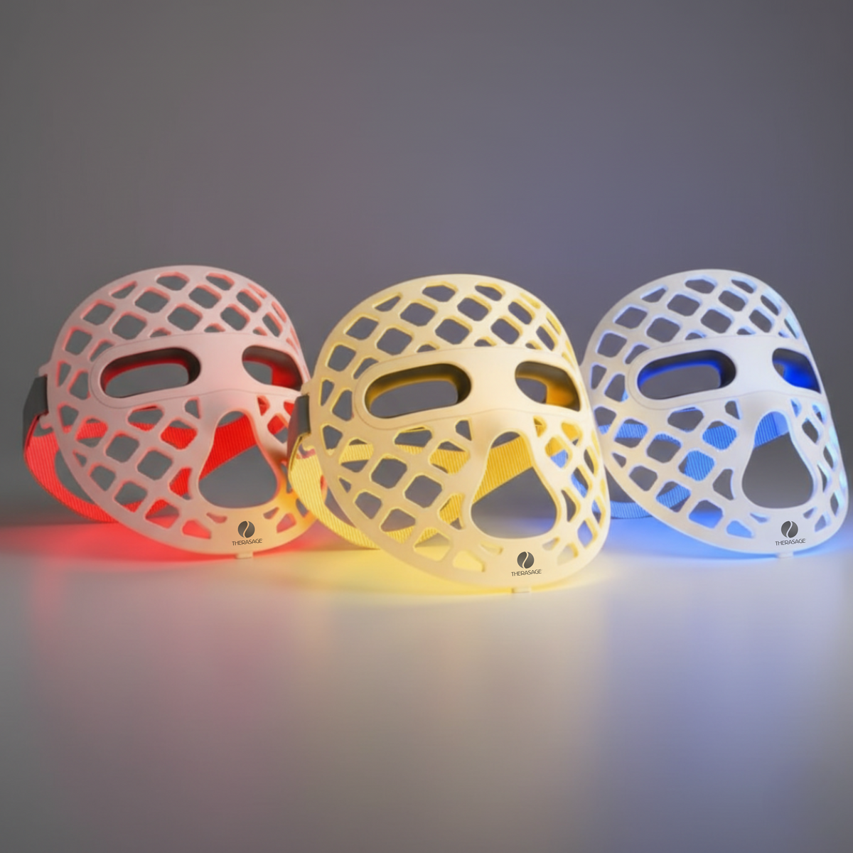 Three TheraGlow Mask2Go+™ LED Light Therapy Face Masks glow red, yellow, and blue against a dark background.