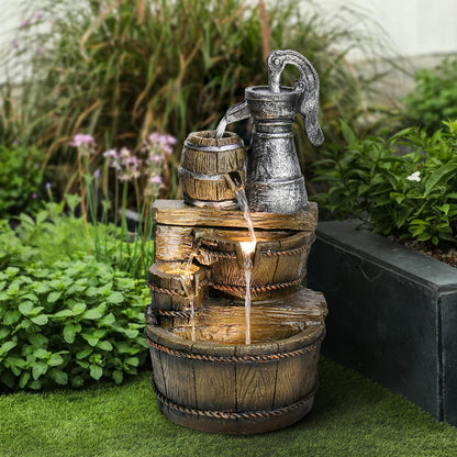 Resin Broken Barrel Rustic Outdoor Fountain 25 Inch LED stands outdoors on grass near a garden bed.