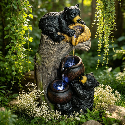 Resin Black Bear Outdoor Water Fountain framed by hanging greenery and white flowers in a garden.