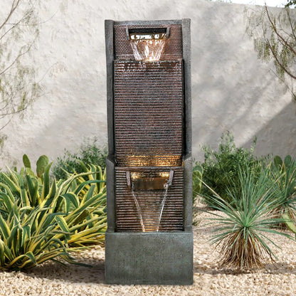 Resin Slim Outdoor Wall Fountain 39 Inch 11 Inch Deep pours water in two tiers among gravel and garden plants.