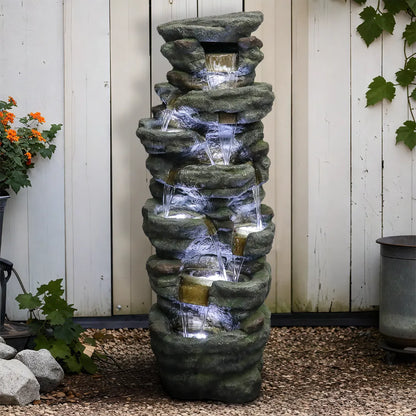 Resin River Rock Outdoor Fountain Pillar 51 Inch 52 lb pours water over stacked gray rocks beside a white garden fence.