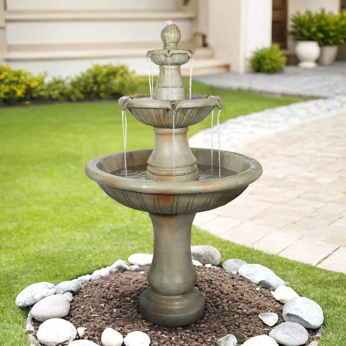 Concrete Fluted 3 Tier Outdoor Water Fountain 51 Inch running in a landscaped lawn beside a stone walkway.