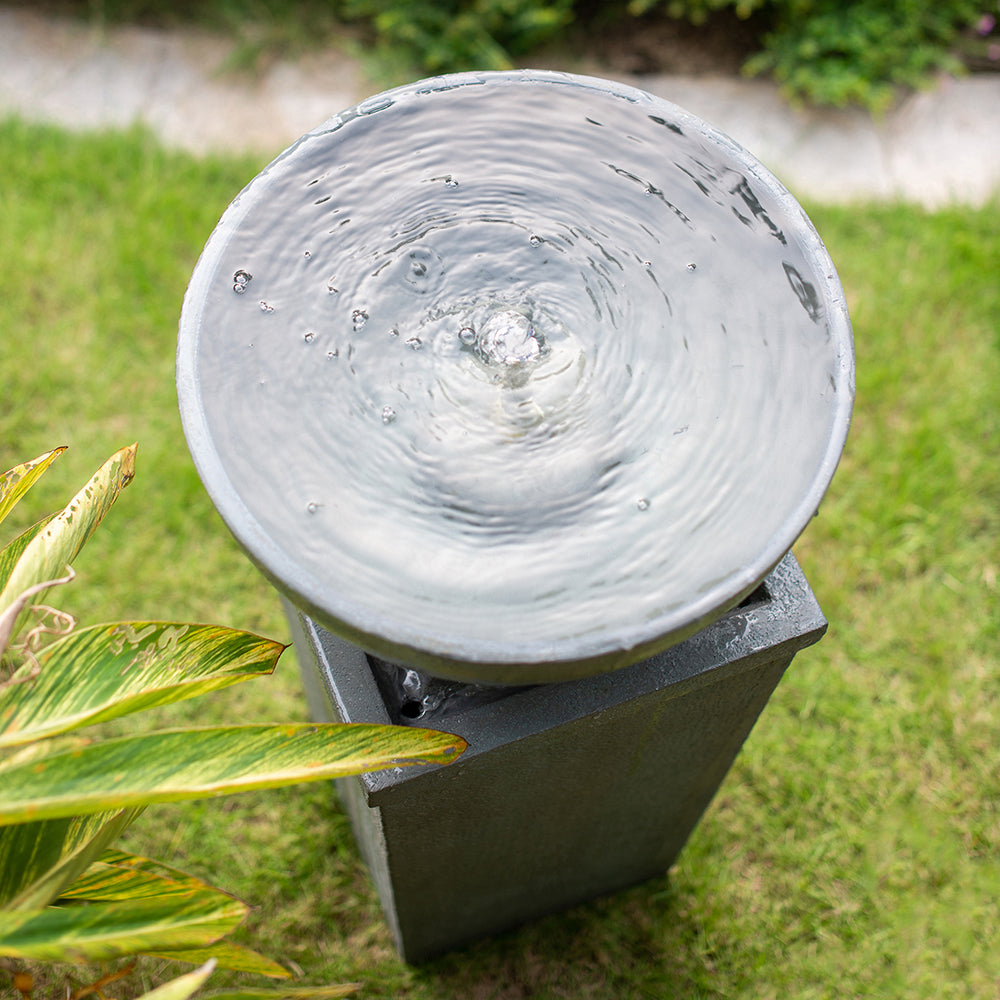 Overhead view of rippling water in the Resin Zen Bowl Pedestal Outdoor Fountain 44 Inch beside a lawn.