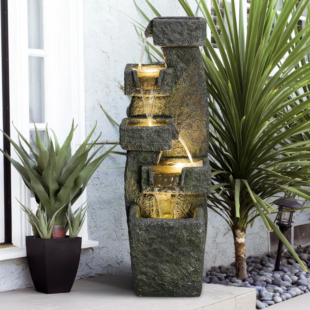 Resin Tiered Outdoor Fountain 5 Tier Modern LED flowing beside potted plants and a window.