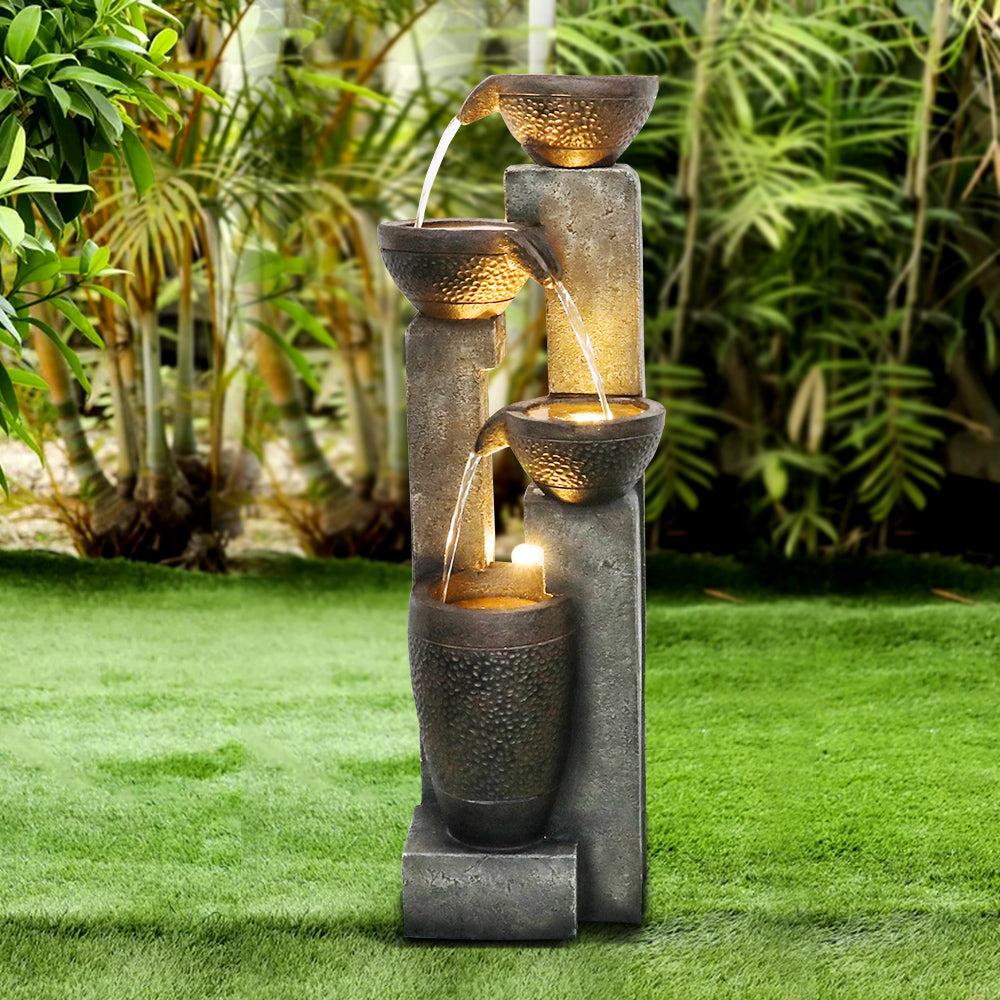 Resin Stacked Clay Pot Outdoor Water Fountain 40 Inch stands on green lawn among tropical plants.