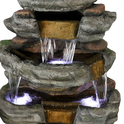 Close-up of Resin Stepped Shale Outdoor Rock Fountain showing water spilling from an upper ledge into a lit basin.
