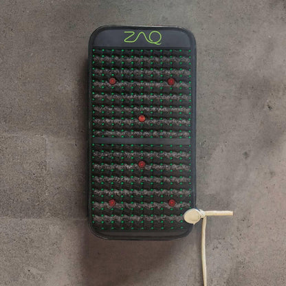 Infrared PEMF Travel Mat viewed from above on a gray floor, with its cord extending to the side.