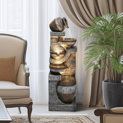 Resin Carved Clay Urn Outdoor Water Fountain 42 Inch stands in a sitting room beside an armchair and potted palm.