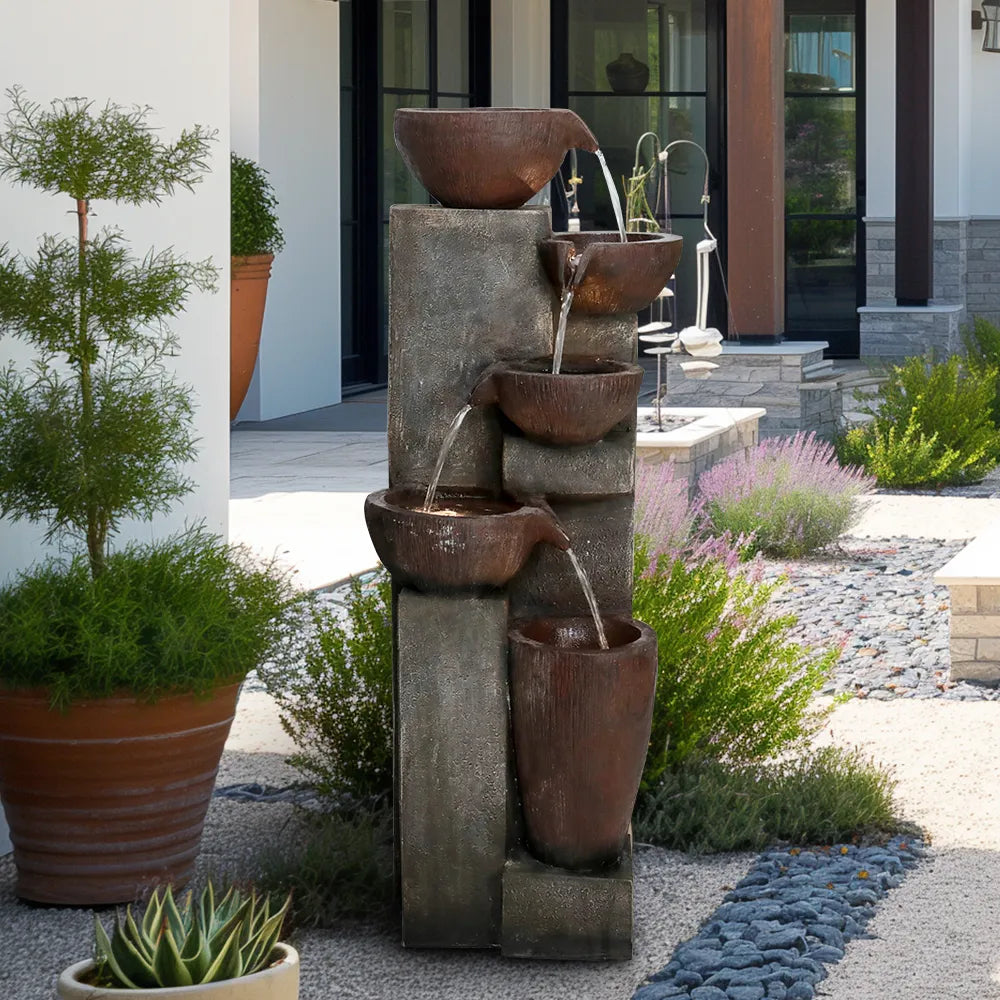 Resin Diagonal Cascading Floor Fountain Outdoor 40 in in a gravel garden near a home entrance and potted greenery.