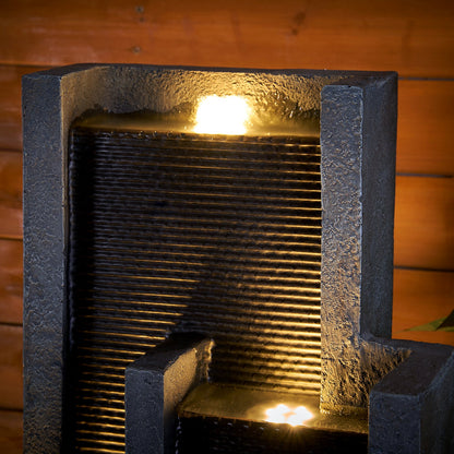 Resin Ribbed Slate Outdoor Water Fountain Quiet 50 in shown close up with glowing water against a wood plank backdrop.