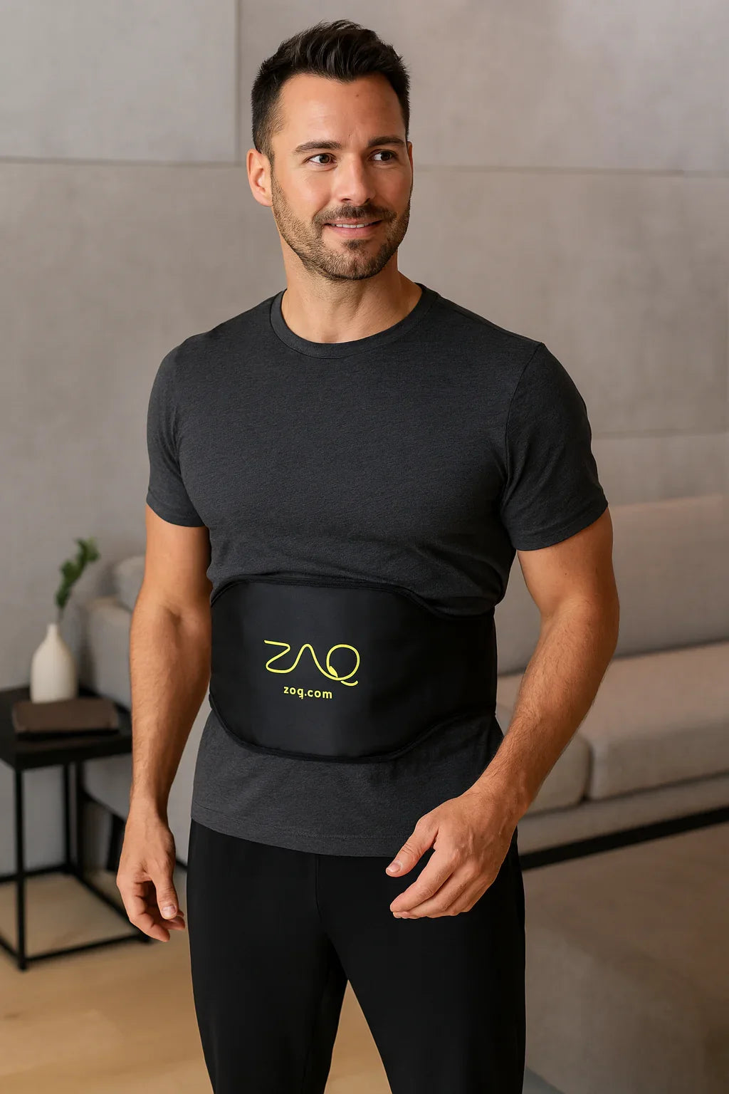 A man wears a black REVA Multifunctional Infrared Heat belt over his shirt in a living room.