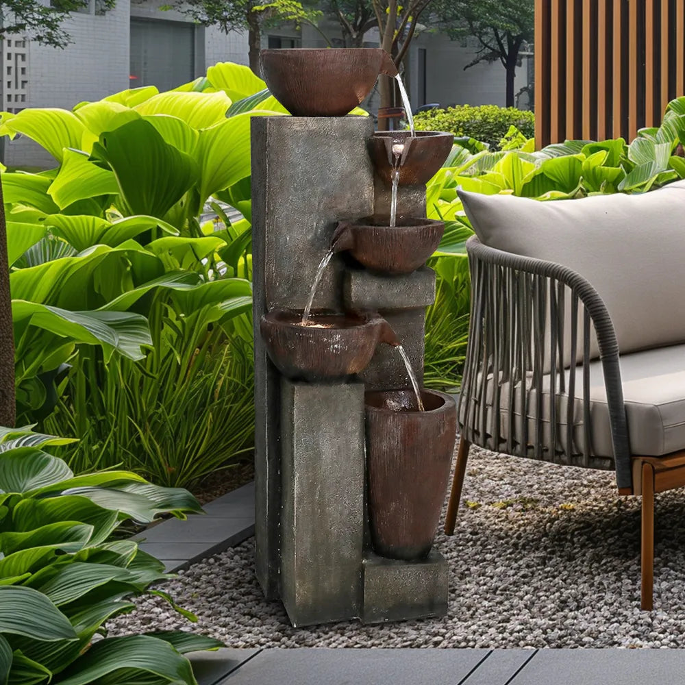 Resin Diagonal Cascading Floor Fountain Outdoor 40 in beside cushioned patio seating and lush green foliage.