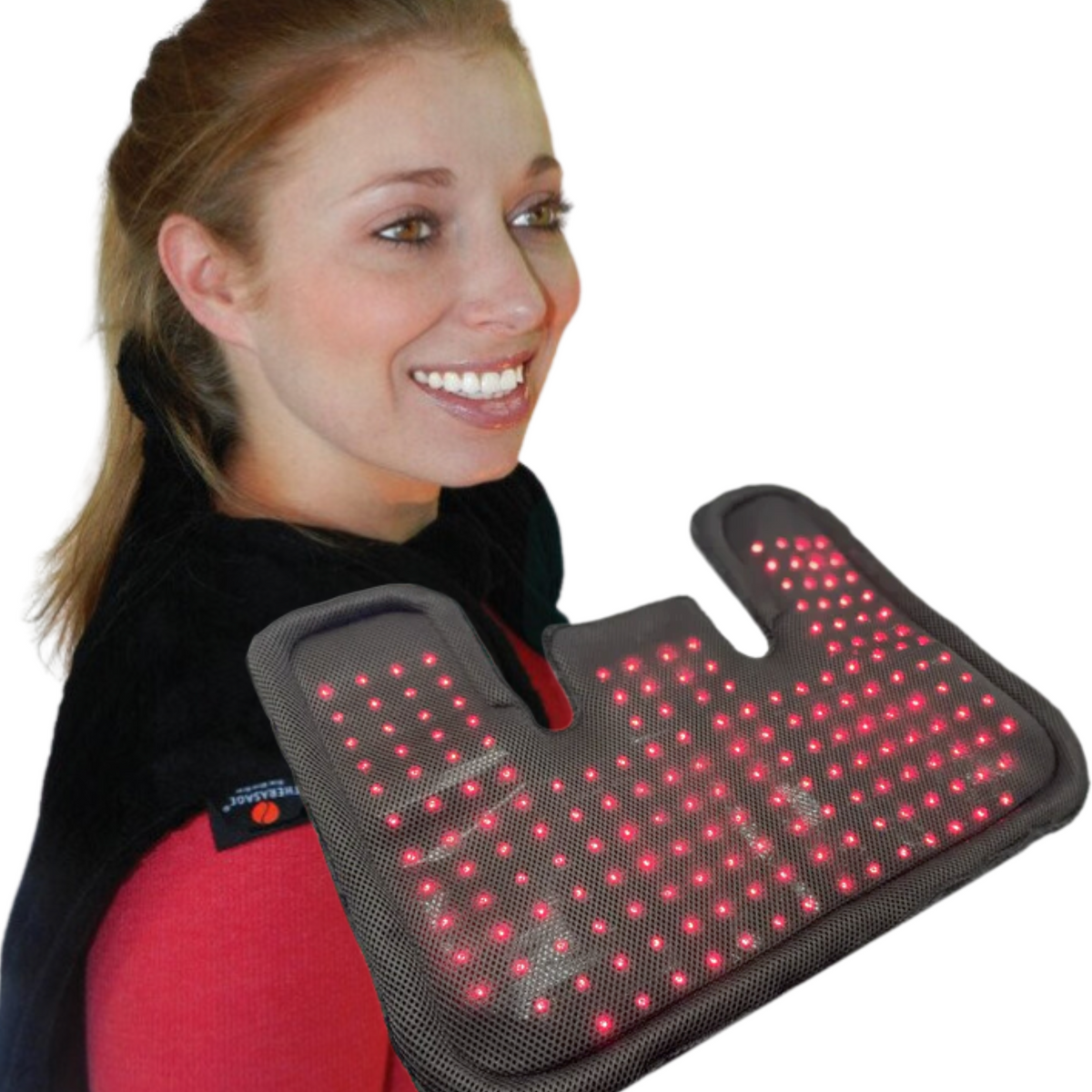 A smiling woman holds the glowing TheraPerfect Pad™ against her shoulder against a white background.