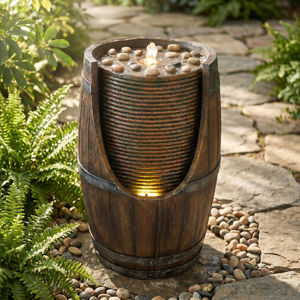 Resin Rustic Barrel Outdoor Water Fountain 24 Inch LED in copper, topped with water and pebbles beside a garden path.