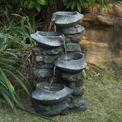 Resin Fluted Basin Tiered Outdoor Water Fountain 650 GPH sitting on grass near plants and rocks.