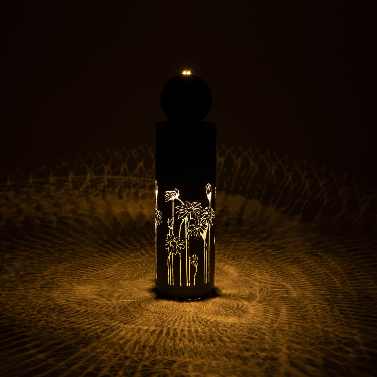Metal Sphere Water Fountain Outdoor glows in the dark, with light shining through its floral cutouts.