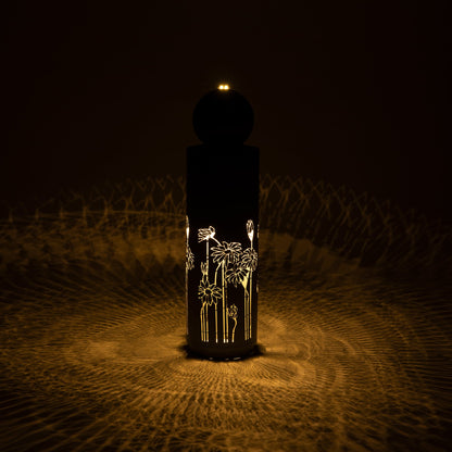 Metal Sphere Water Fountain Outdoor glows in the dark, with light shining through its floral cutouts.