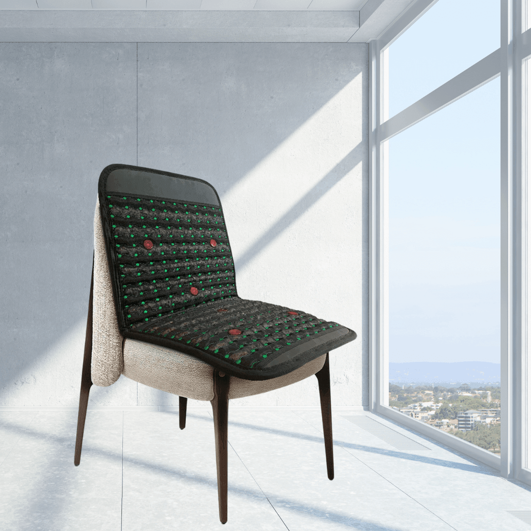Infrared PEMF Travel Mat covering the seat and back of a chair beside a large sunlit window.