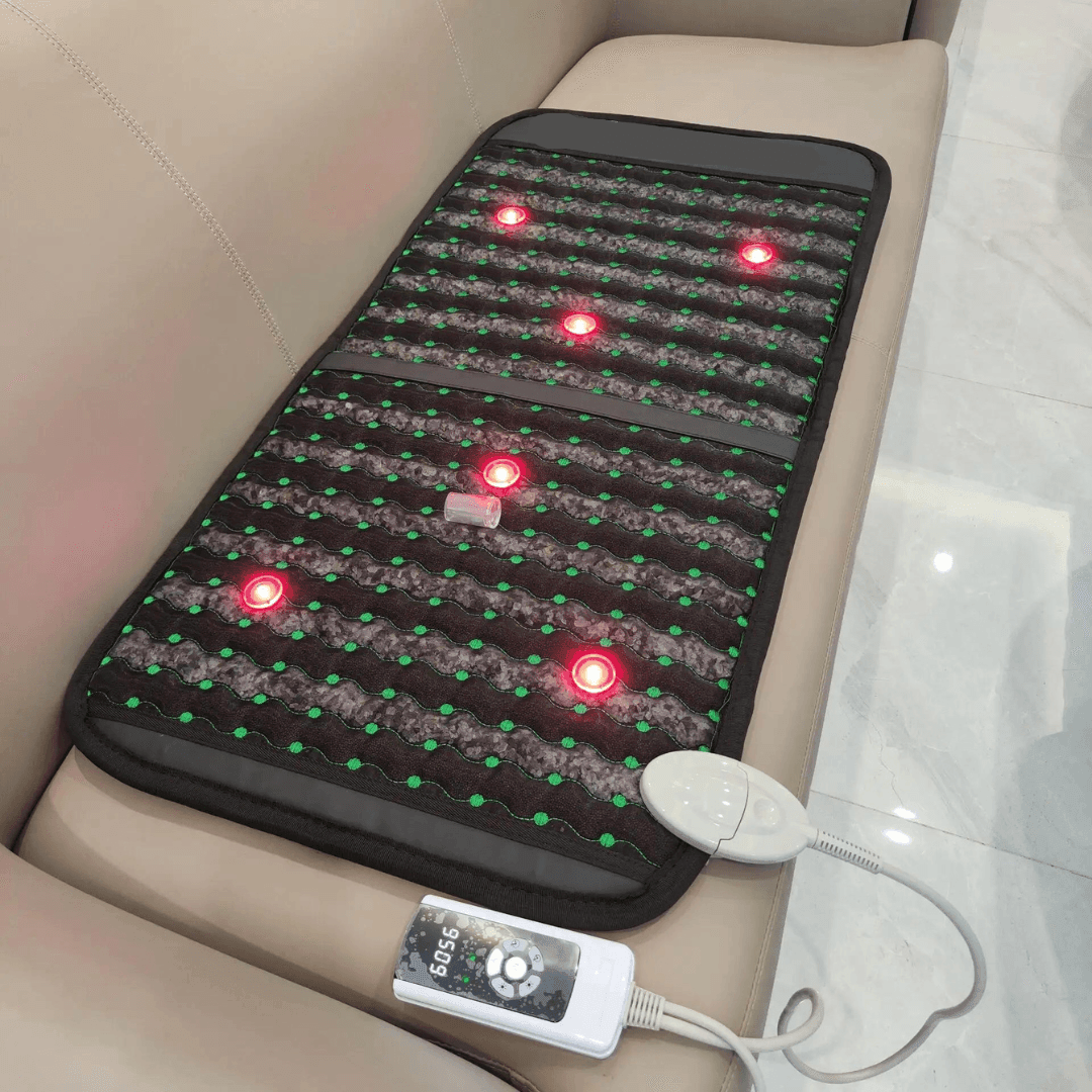Infrared PEMF Travel Mat spread across a beige sofa, with glowing red points and a wired controller beside it.